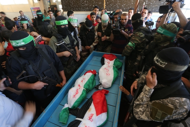 The bodies of the three children surrounded by members of Hamas's al-Qassam Brigades prior to their funeral on Saturday (Mohammed Asad/MEE).